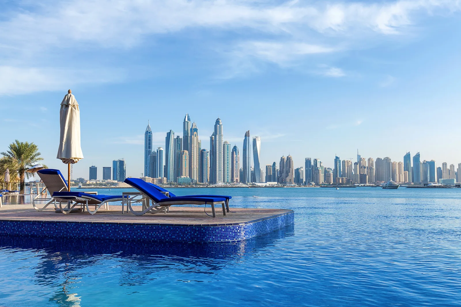 Infinity pool with sun loungers overlooking the Dubai Marina skyline.
